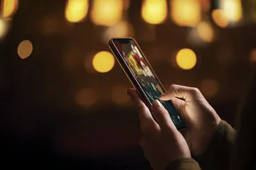 A woman smiling by bright slot machines showing lucky symbols, showcasing the exciting slot offerings at JLPLUS.